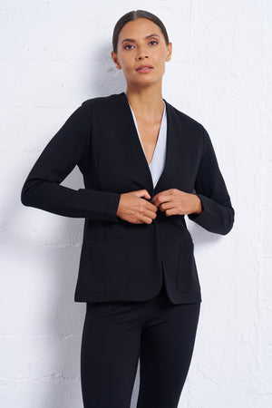 Woman wearing a black blazer over a white shirt on a light gray background