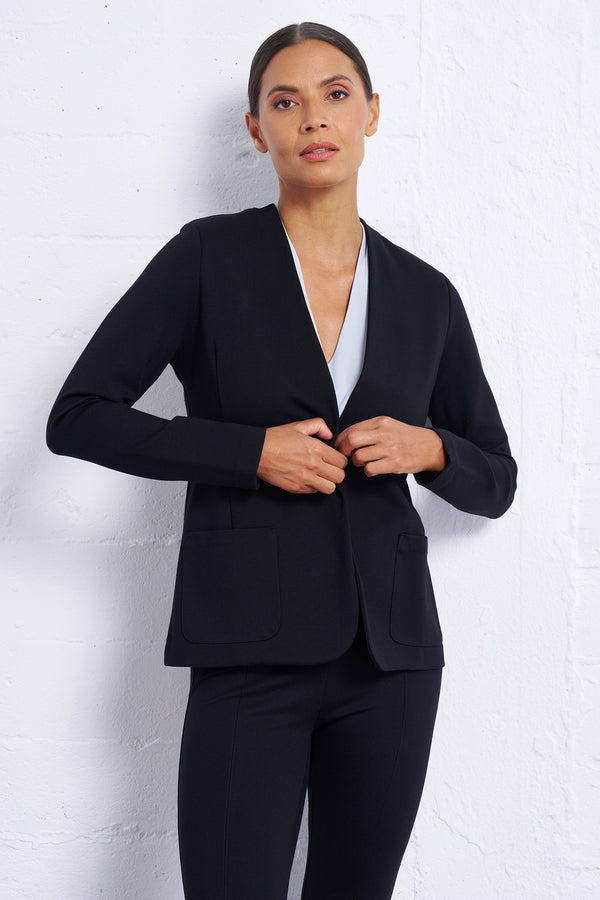 Woman wearing a black blazer over a white shirt on a light gray background