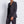 Load image into Gallery viewer, Woman wearing a dark gray suit against a white brick wall
