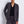 Load image into Gallery viewer, Woman wearing a gray suit against a white brick wall
