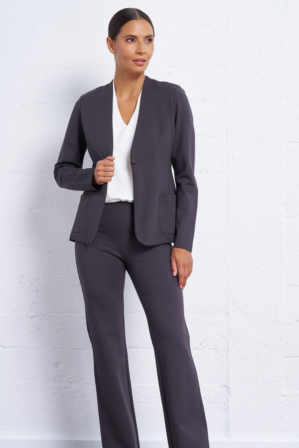 Woman wearing a gray suit against a white brick wall
