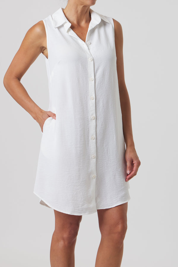Woman wearing a white sleeveless dress against a plain background